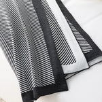 Cette image montre des tissus noirs et blancs avec des motifs rayés et en zigzag, créant un effet visuel dynamique et contrasté.