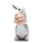 Lapin blanc assis et tenant un œuf de Pâques rose et or.