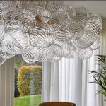 suspension lumineuse moderne verre transparent chaîne dorée led acier poli contemporain lumière chaude chambre