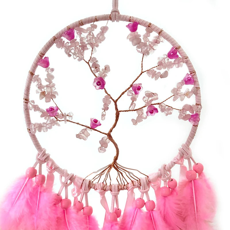 Une magnifique suspension décorative en forme d'arbre de vie, ornée de fleurs roses et de perles, suspendue par des plumes rose vif.