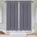 Deux panneaux de rideaux gris en velours avec finitions pompons installés dans une salle de bain au style moderne et épuré.
