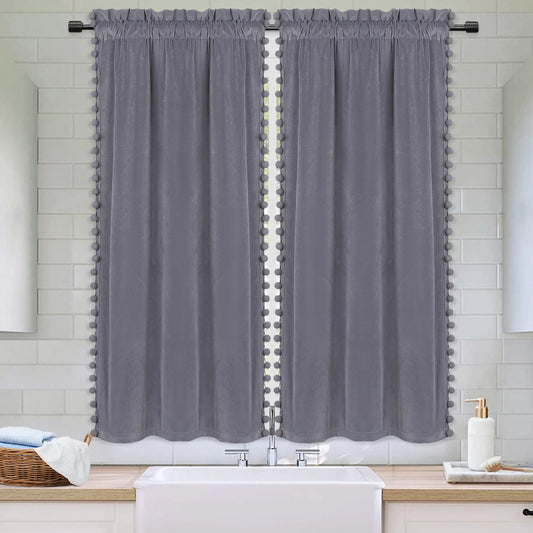 Deux panneaux de rideaux gris en velours avec finitions pompons installés dans une salle de bain au style moderne et épuré.