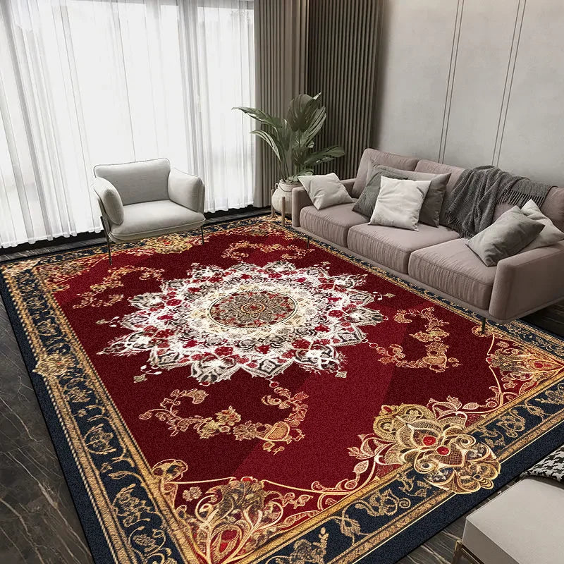 Un tapis de luxe orné de motifs floraux rouges et dorés, posé dans un salon spacieux avec un canapé gris et un fauteuil assorti, créant une atmosphère élégante et chaleureuse.