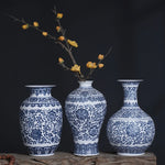 Un trio de vases en porcelaine bleu et blanc ornés de motifs floraux élégants sur un fond sombre, créant une atmosphère de raffinement et de grâce.