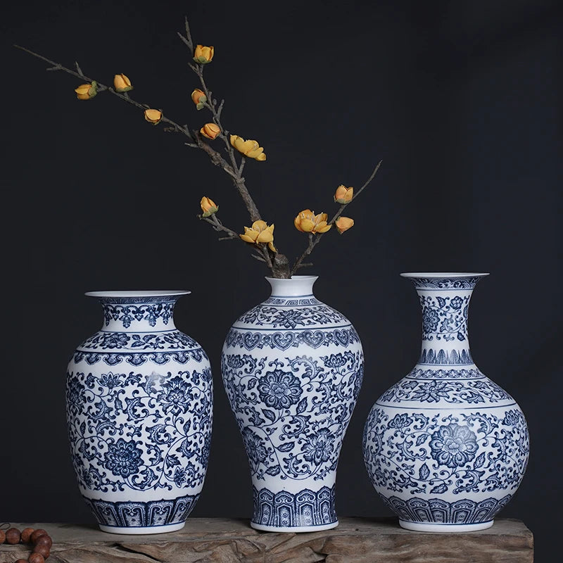 Un trio de vases en porcelaine bleu et blanc ornés de motifs floraux élégants sur un fond sombre, créant une atmosphère de raffinement et de grâce.