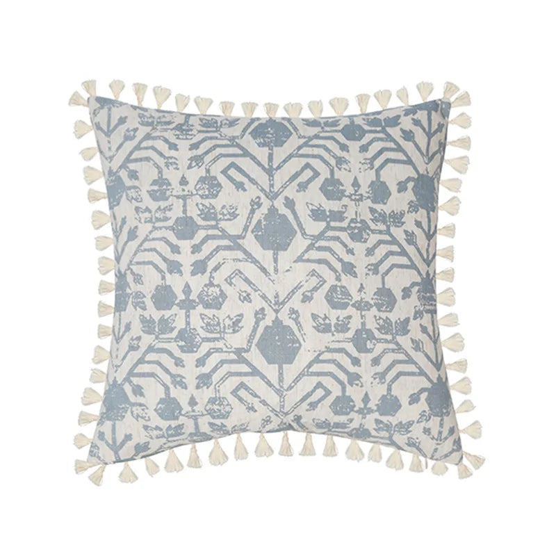 Coussin ornemental gris et blanc avec motif géométrique et pompons décoratifs.