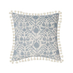 Coussin ornemental gris et blanc avec motif géométrique et pompons décoratifs.