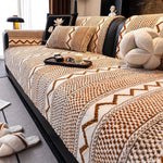 Un lit recouvert d'une couverture beige en maille ornementée, avec des coussins décoratifs noirs et blancs, sur lequel sont posés un plateau avec une bougie et des accessoires, dans un cadre cocooning et chaleureux.