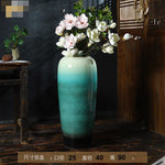 Vase en céramique vert dégradé avec de magnifiques fleurs blanches et roses.