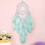 Un magnifique attrape-rêves décoratif composé de plumes douces de couleur menthe, avec des anneaux tissés et des accents brillants, créant une œuvre d'art captivante pour décorer un espace intérieur.