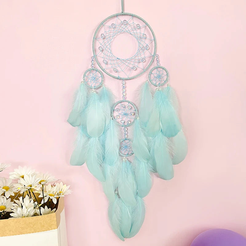 Un magnifique attrape-rêves décoratif composé de plumes douces de couleur menthe, avec des anneaux tissés et des accents brillants, créant une œuvre d'art captivante pour décorer un espace intérieur.