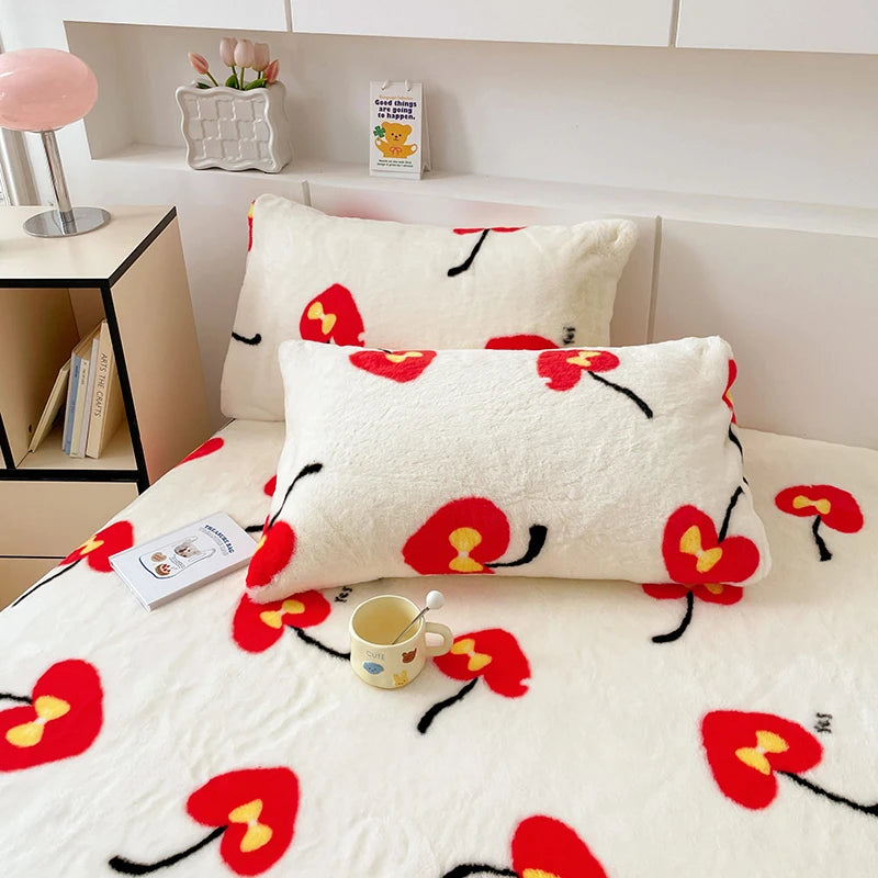 Une couverture et des oreillers moelleux aux motifs de fleurs rouges vives et de tiges noires sur un lit douillet.