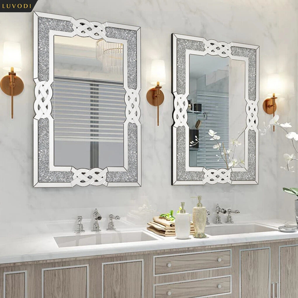 Deux miroirs muraux élégants aux cadres argentés ornés de motifs entrelacés, reflétant une salle de bain avec un meuble-lavabo en bois nuancé et des accessoires assortis, créant une ambiance raffinée et harmonieuse.