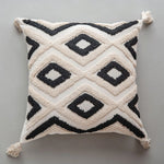 Coussin décoratif blanc et noir avec des motifs géométriques entrelacés.