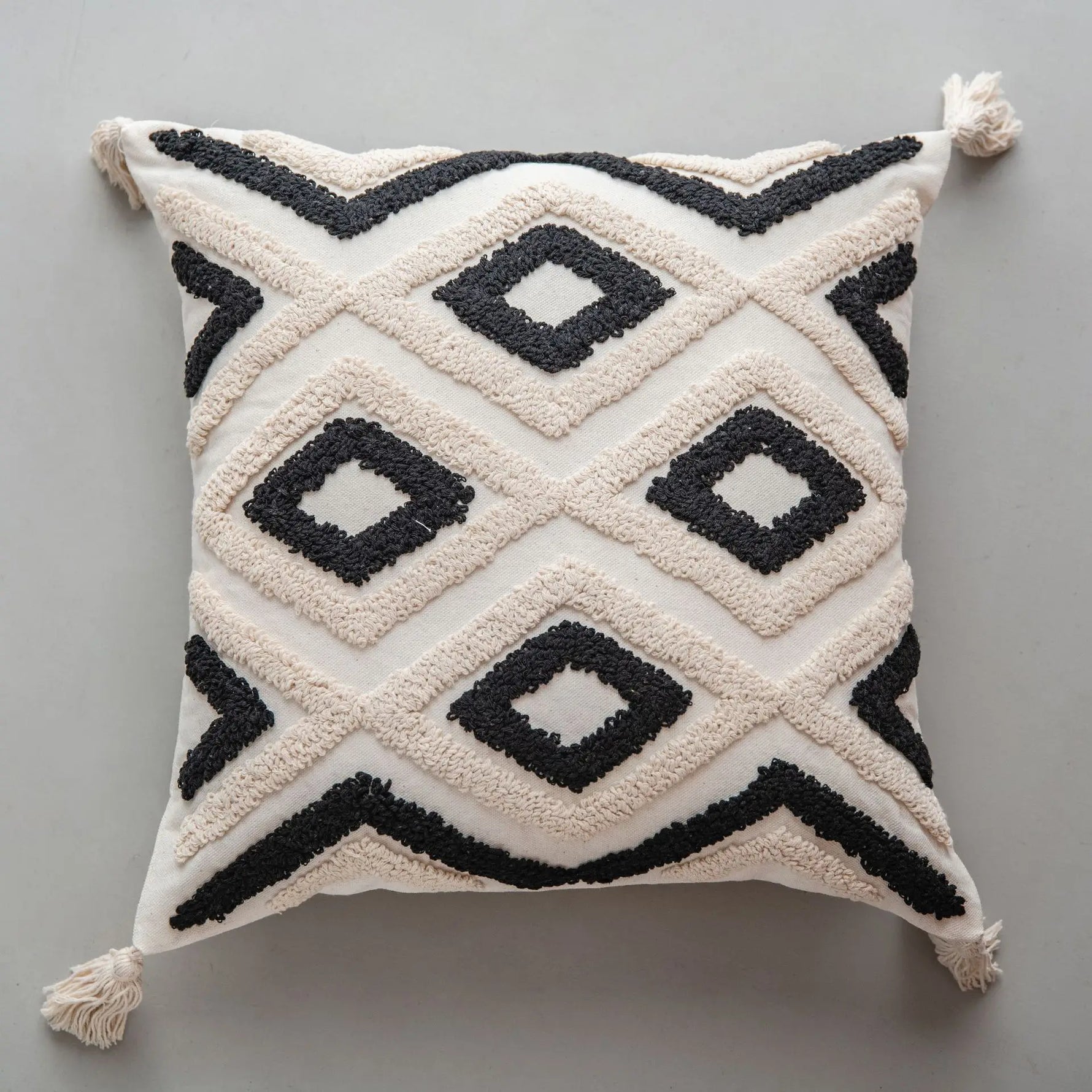 Coussin décoratif blanc et noir avec des motifs géométriques entrelacés.