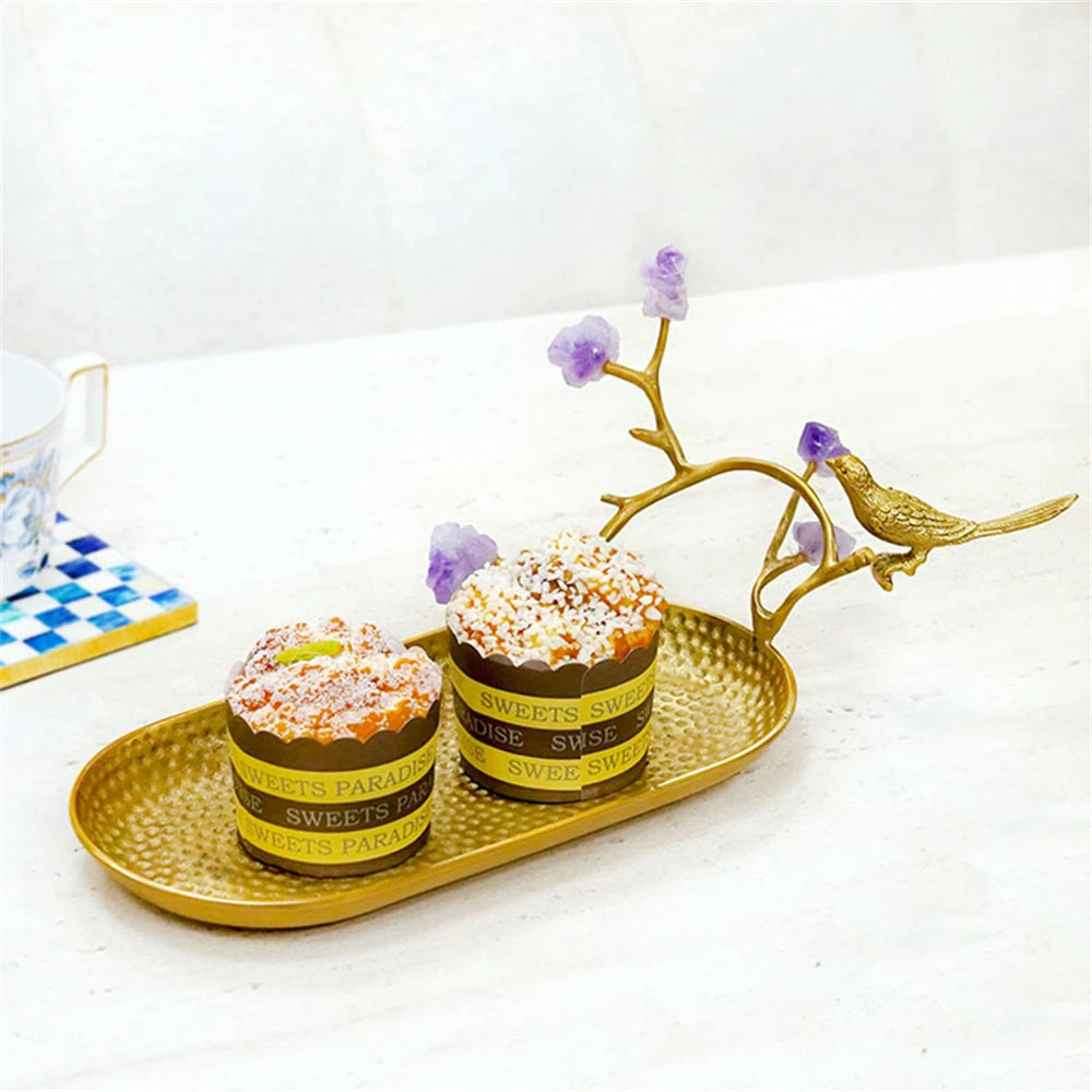 Des gâteaux de luxe sur un plateau doré décoré d'une branche de fleurs violettes, évoquant un dessert sophistiqué et exquis.