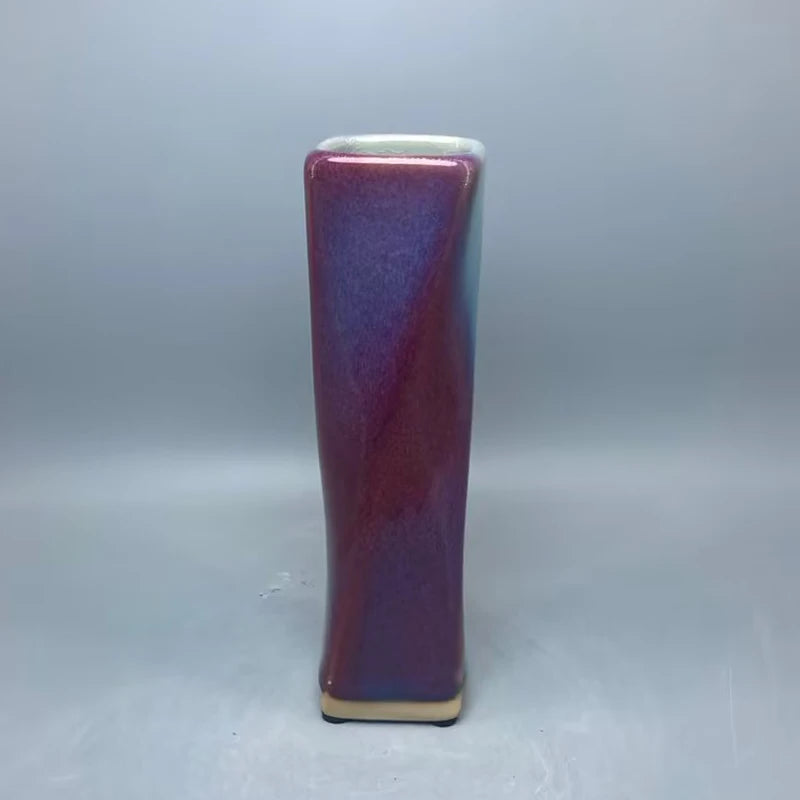 Vase en céramique de couleur pourpre brillante avec une forme élancée et élégante.