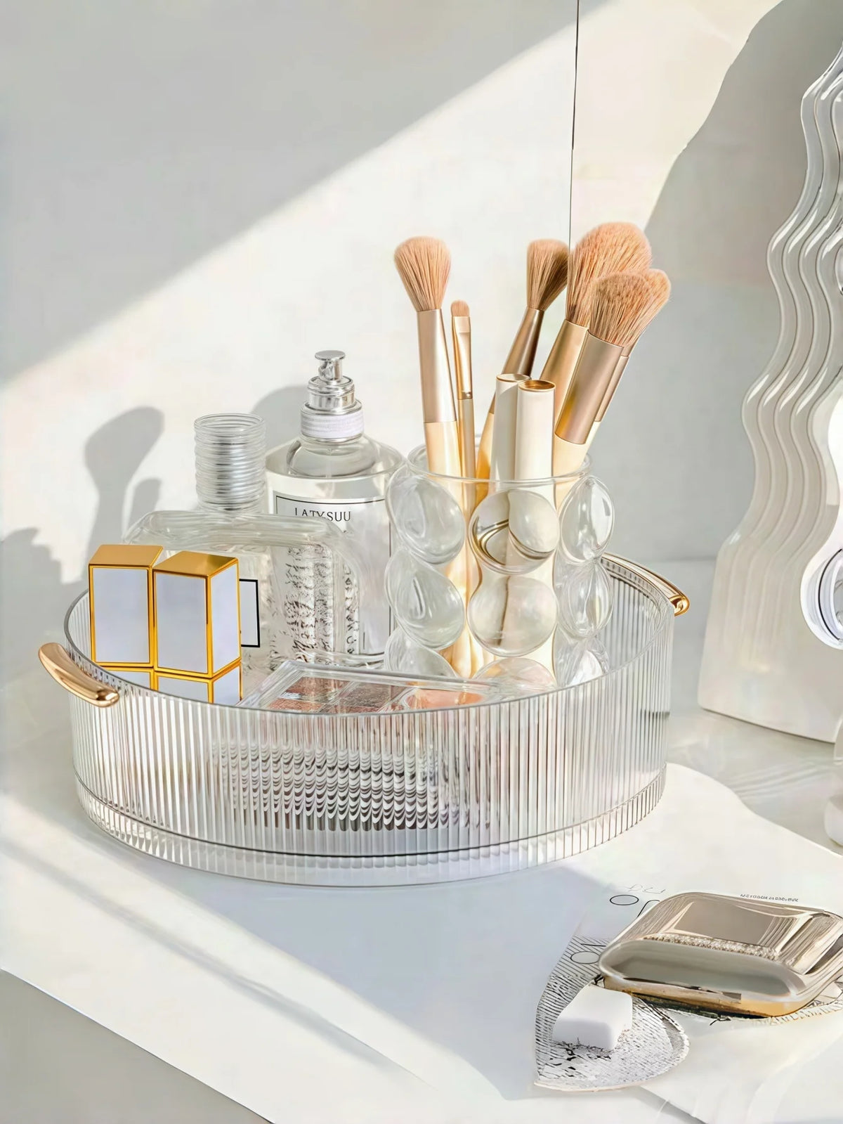 organisateur rotatif transparent cosmétiques parfums rayures verticales moderne poignées dorées brosse maquillage flacon parfum
