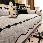 Lit confortable avec linge de lit décoré de motifs de cœurs et de papillons noirs sur fond gris clair, orné d'un coussin assorti et d'une tasse design sur la table basse.