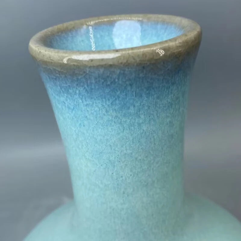 Vase décoratif en céramique bleu turquoise avec un rebord doré.