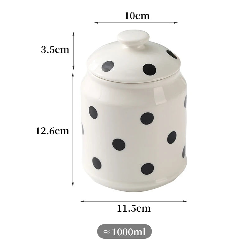 Pot décoratif en céramique blanche avec des motifs de points noirs, d'un volume approximatif de 1000 ml et de dimensions 10 cm de diamètre et 12,6 cm de hauteur.