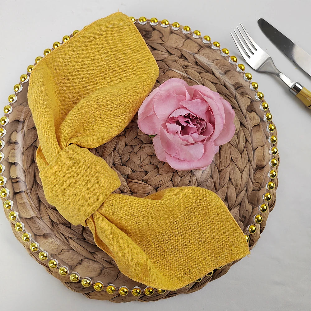 Superbe arrangement de table avec une serviette en tissu jaune, une jolie fleur rose et une décoration de table en tressage de fibres naturelles.
