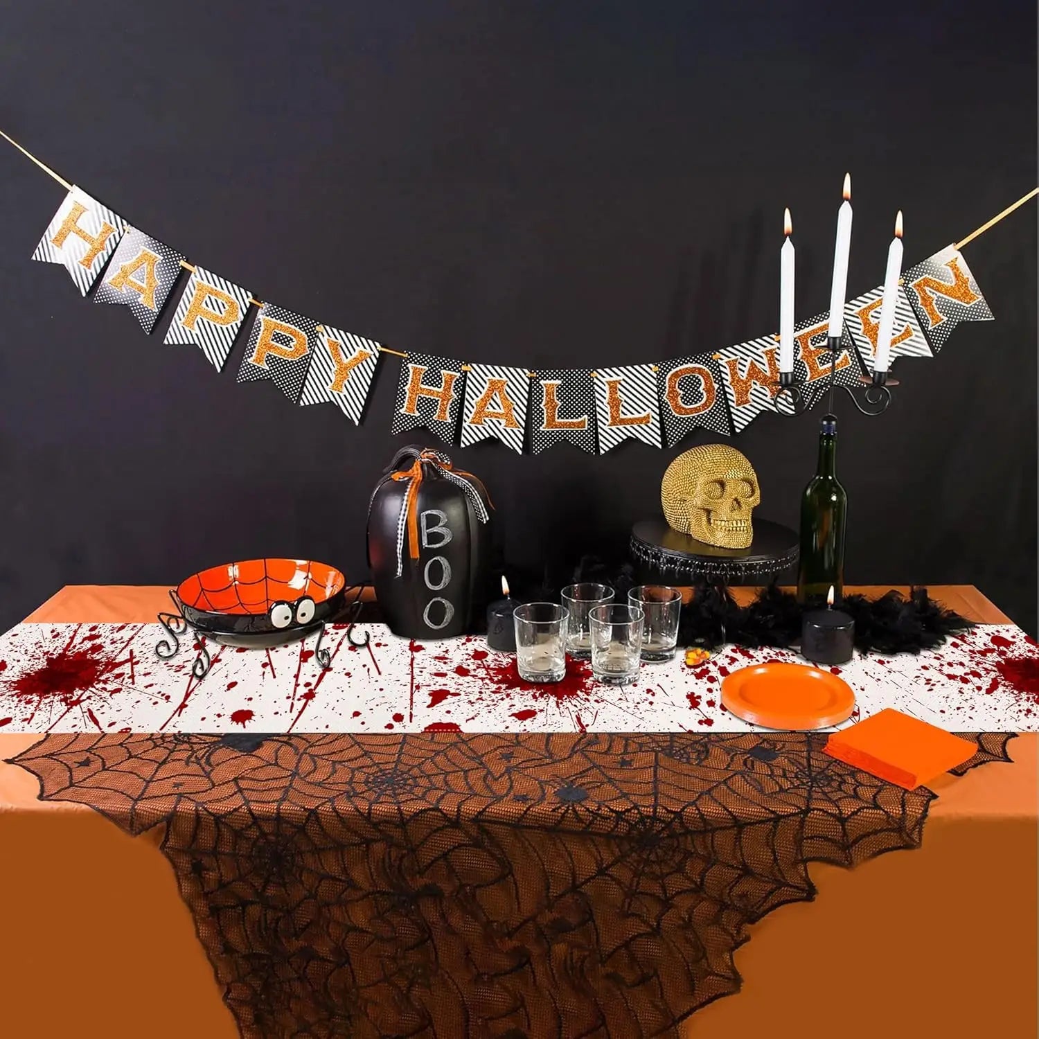 Décoration festive d'Halloween avec bannière, bougies, crâne décoratif et accessoires effrayants sur une table.