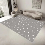 Un tapis gris décoré d'étoiles blanches dans un salon moderne et minimaliste, avec un canapé gris et des accents décoratifs.