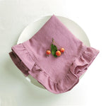 Nappes en lin rose avec petites cerises vertes sur une assiette blanche.