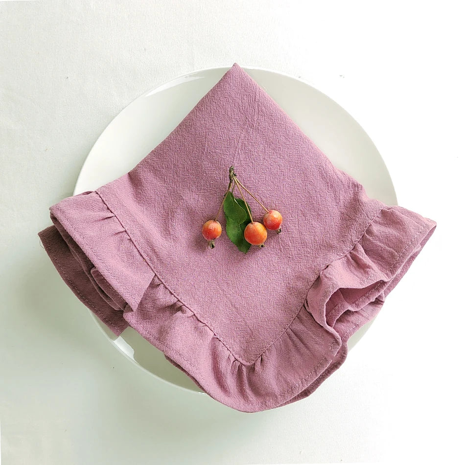 Nappes en lin rose avec petites cerises vertes sur une assiette blanche.