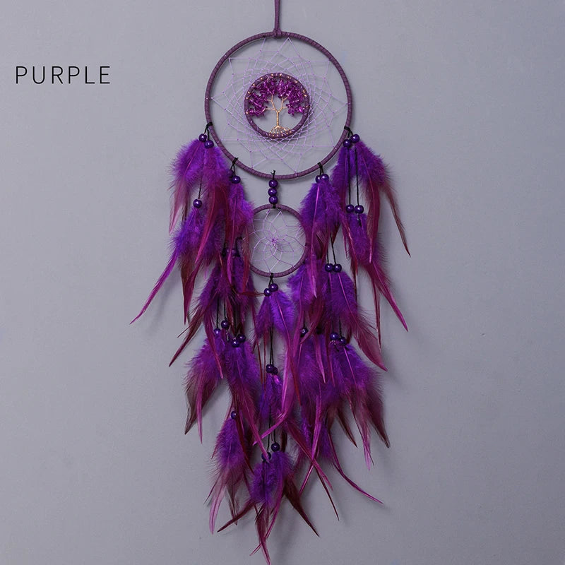 Un attrapeur de rêves suspendu aux tons violets, orné d'un arbre de vie au centre, entouré de longues plumes violettes et rouges.