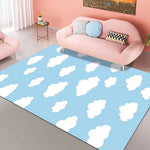 Un tapis bleu représentant des nuages blancs flottants dans un ciel clair, plaçant un accent de fraîcheur et de paix dans une pièce aux tons roses.