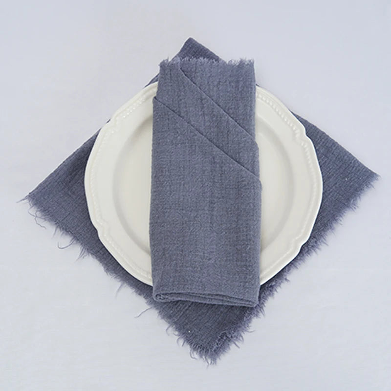 Sur une assiette blanche, une serviette grise pliée avec soin crée une atmosphère élégante et minimaliste.