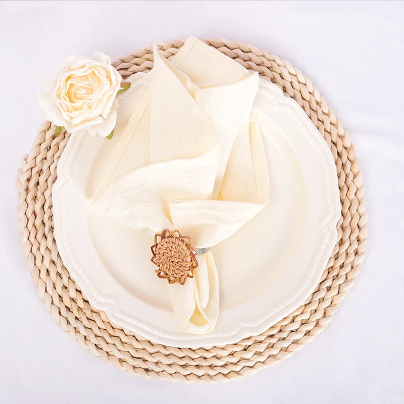 Une délicate serviette blanche ornée d'une rose et d'un jonc tressé, créant une mise en scène élégante et épurée.