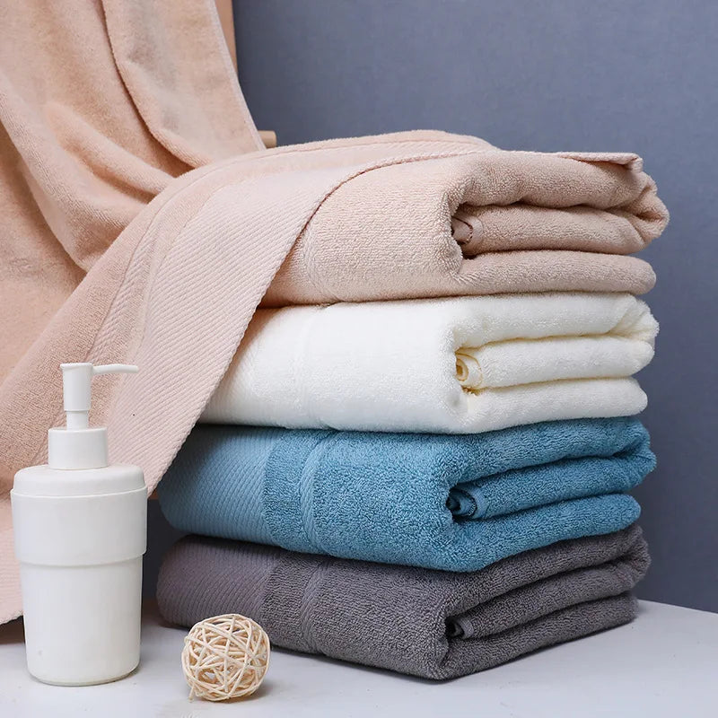 Pile de serviettes de bain douces de couleurs pastel, accompagnées d'un distributeur de savon et d'une décoration en osier, créant une ambiance apaisante dans la salle de bain.