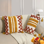 Des coussins en tricot colorés, décorés avec des motifs géométriques et des franges, créant une ambiance chaleureuse et confortable dans le salon.