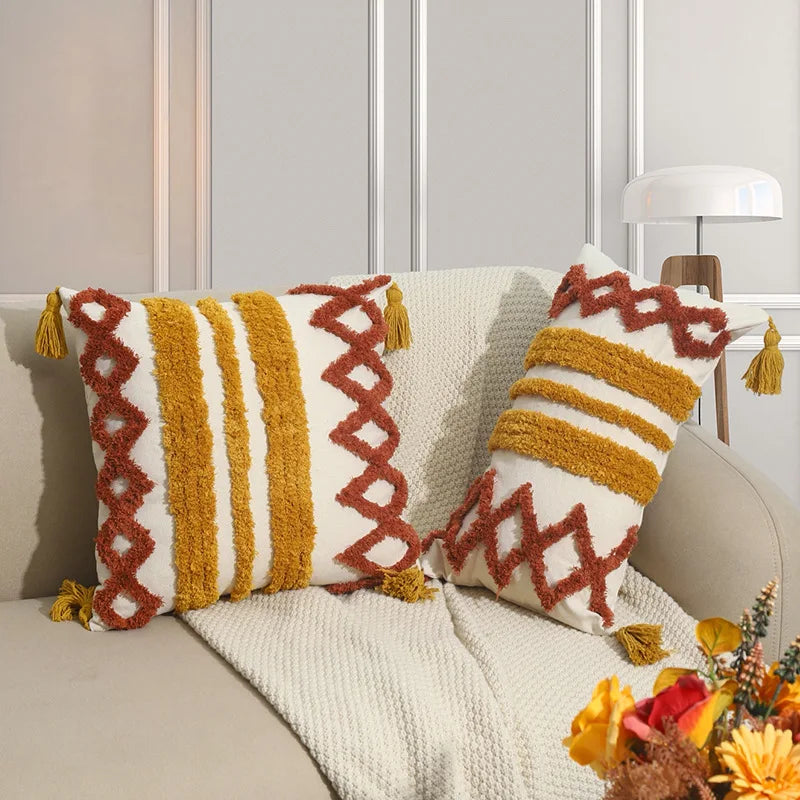 Des coussins en tricot colorés, décorés avec des motifs géométriques et des franges, créant une ambiance chaleureuse et confortable dans le salon.