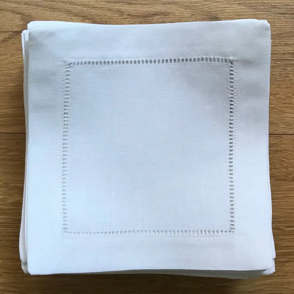 Serviette blanche texturée avec un motif de points cousus délicats sur le bord.