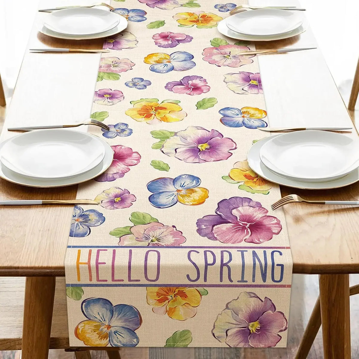 Une nappe de table colorée avec de beaux motifs de fleurs de printemps dans des tons de violet, jaune et bleu, complétée par le texte "Hello Spring" pour célébrer l'arrivée de la saison printanière.