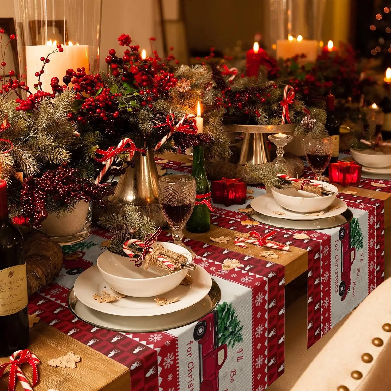 Cette image montre une belle table de Noël décorée avec une composition florale de brindilles de sapin, de baies rouges et de bougies allumées, ainsi que des cadeaux emballés dans du papier cadeau rouge et blanc festif.