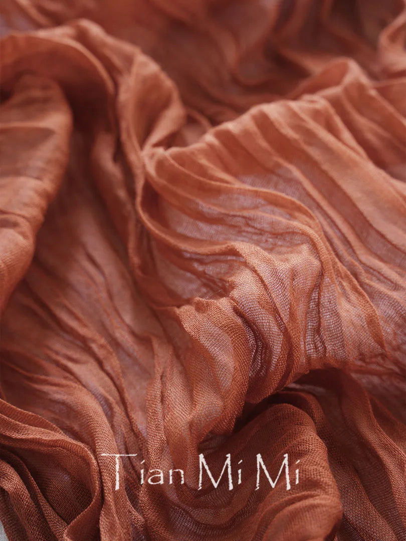 Texture riche et moirée du tissu plissé couleur terracotta avec le logo de la marque "Tian Mi Mi" imprimé discrètement.