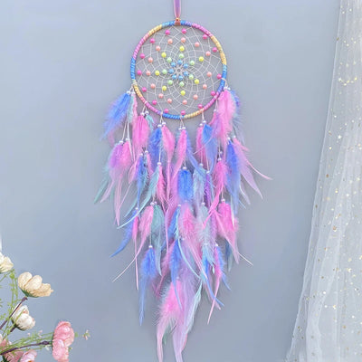 Le capteur de rêves multicolore orné de plumes roses, bleues et jaunes crée une atmosphère magique et apaisante.