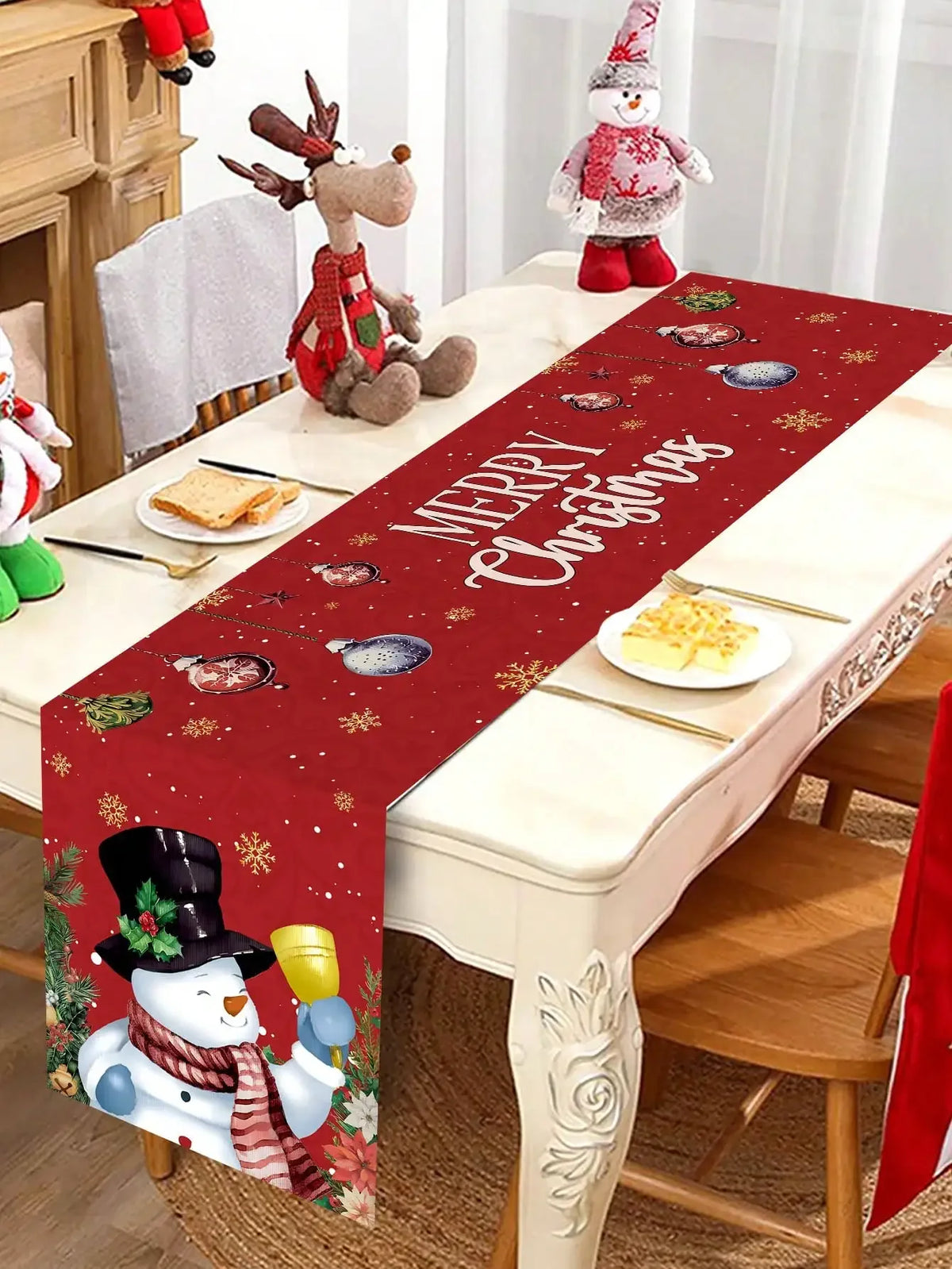 Table de Noël ornée de figurines décoratives et d'une nappe imprimée d'un motif de Noël avec texte en anglais "Merry Christmas". L'ensemble crée une atmosphère festive et chaleureuse pour les fêtes de fin d'année.