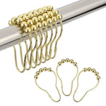 Crochets dorés pour rideaux suspendus sur une tringle métallique, avec perles coulissantes pour une ouverture fluide.