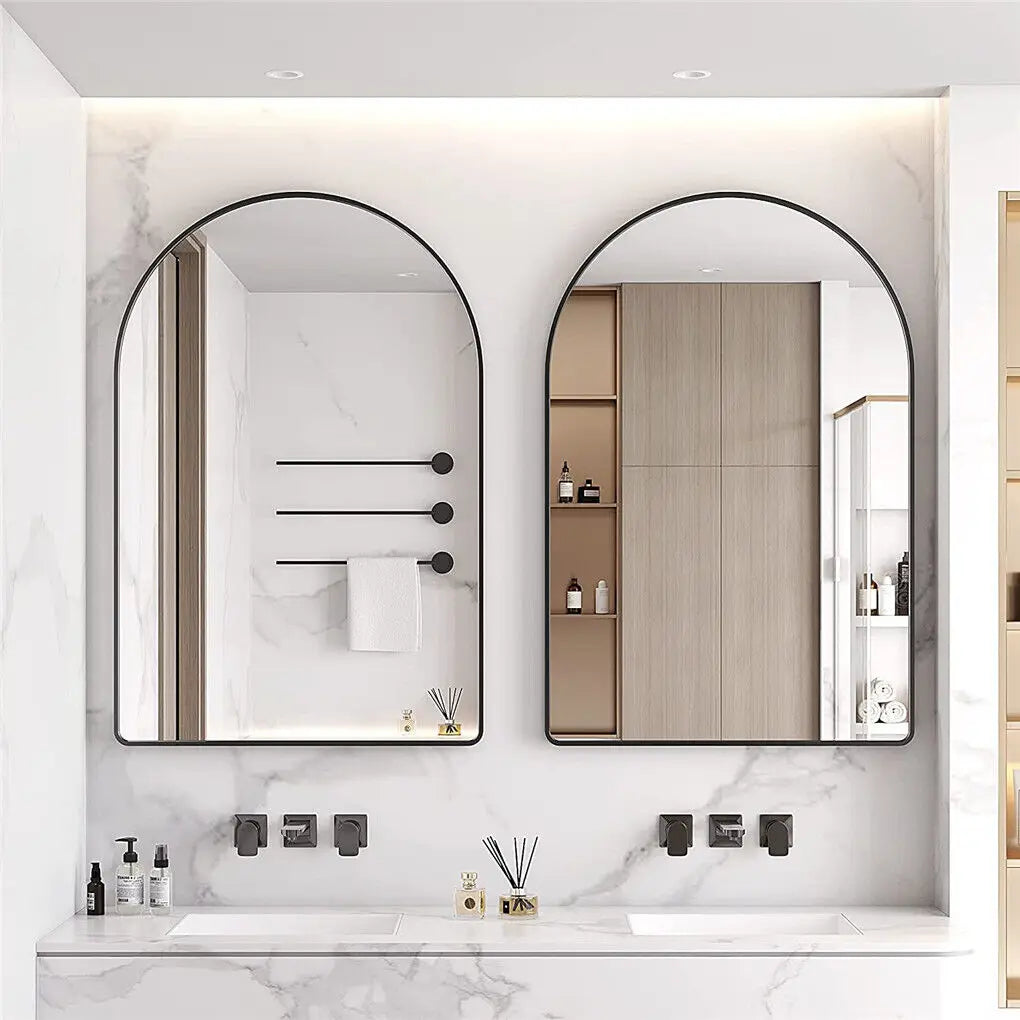 Un intérieur de salle de bain moderne et épuré avec deux miroirs encadrés de métal noir, des étagères encastrées et une vasque blanche posée sur un plan de travail en marbre.
