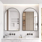 Un intérieur de salle de bain moderne et épuré avec deux miroirs encadrés de métal noir, des étagères encastrées et une vasque blanche posée sur un plan de travail en marbre.
