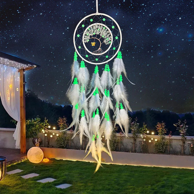 Un capteur de rêves lumineux suspendu dans un paysage nocturne étoilé, décoré de plumes blanches et de perles vertes scintillantes.