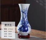 Vase en porcelaine blanche avec un décor peint à la main en bleu, représentant une scène naturelle avec des plantes. Cet objet de décoration ajoute une touche élégante et raffinée à l'intérieur.