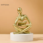 statue résine figure humaine assise livre ouvert beige clair doré texture granuleuse abstrait moderne