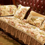 Un canapé capitonné en cuir marron foncé avec des coussins aux motifs floraux dorés et beiges, créant une ambiance chaleureuse et luxueuse.